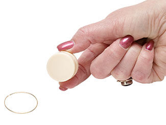 a hand holding a round object next to a ring of wire